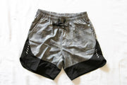 This image displays a pair of men's shorts, featuring a sleek grey color with contrasting black accents. The shorts are designed with a comfortable, elastic waistband and a secure drawstring to ensure a snug fit.