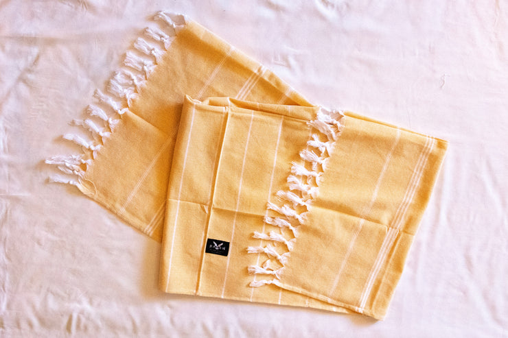 Yellow beach towel with fringes on a white background