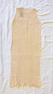 back of beige knitted dress / bathing suit cover on a white textured 