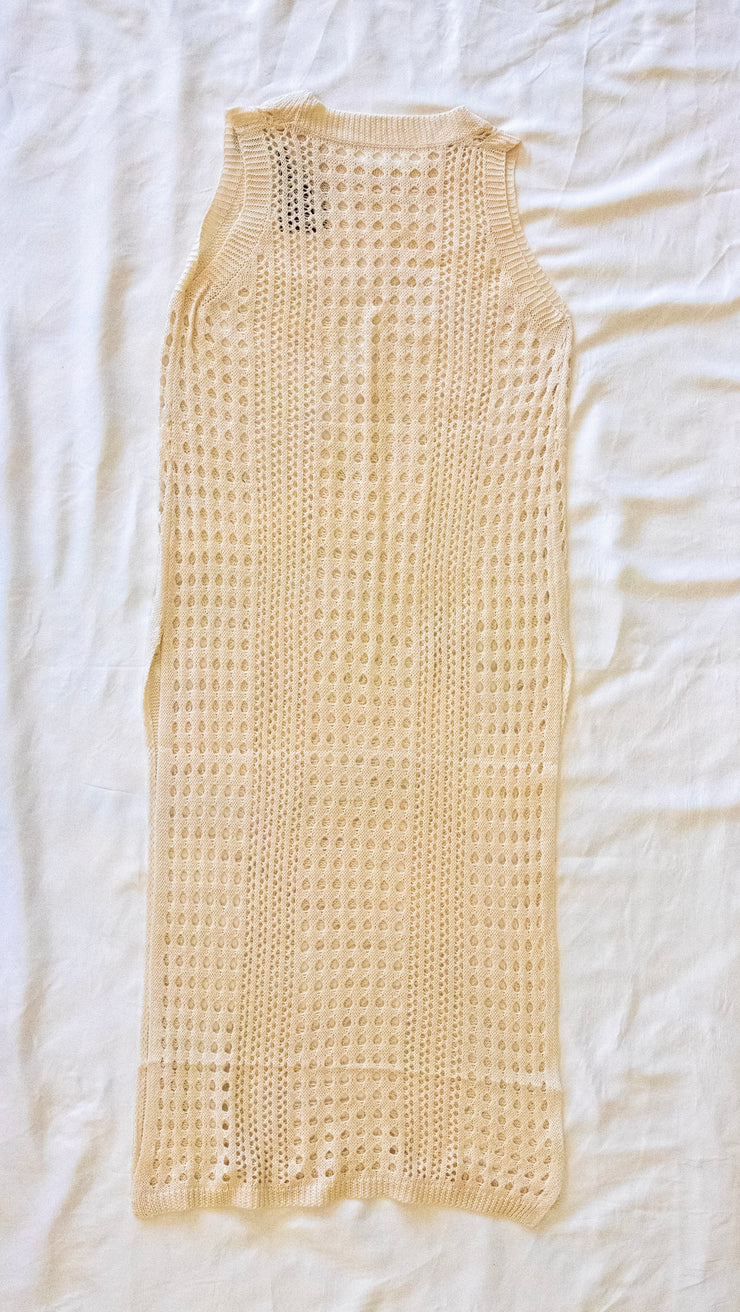 back of beige knitted dress / bathing suit cover on a white textured 
